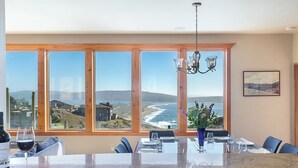 A dining area with a large window overlooking a coastal landscape.