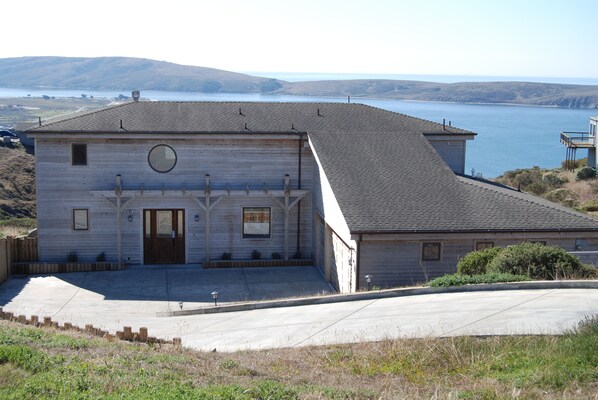 A two-story building with a garage, a small porch, and a view of a body of water.