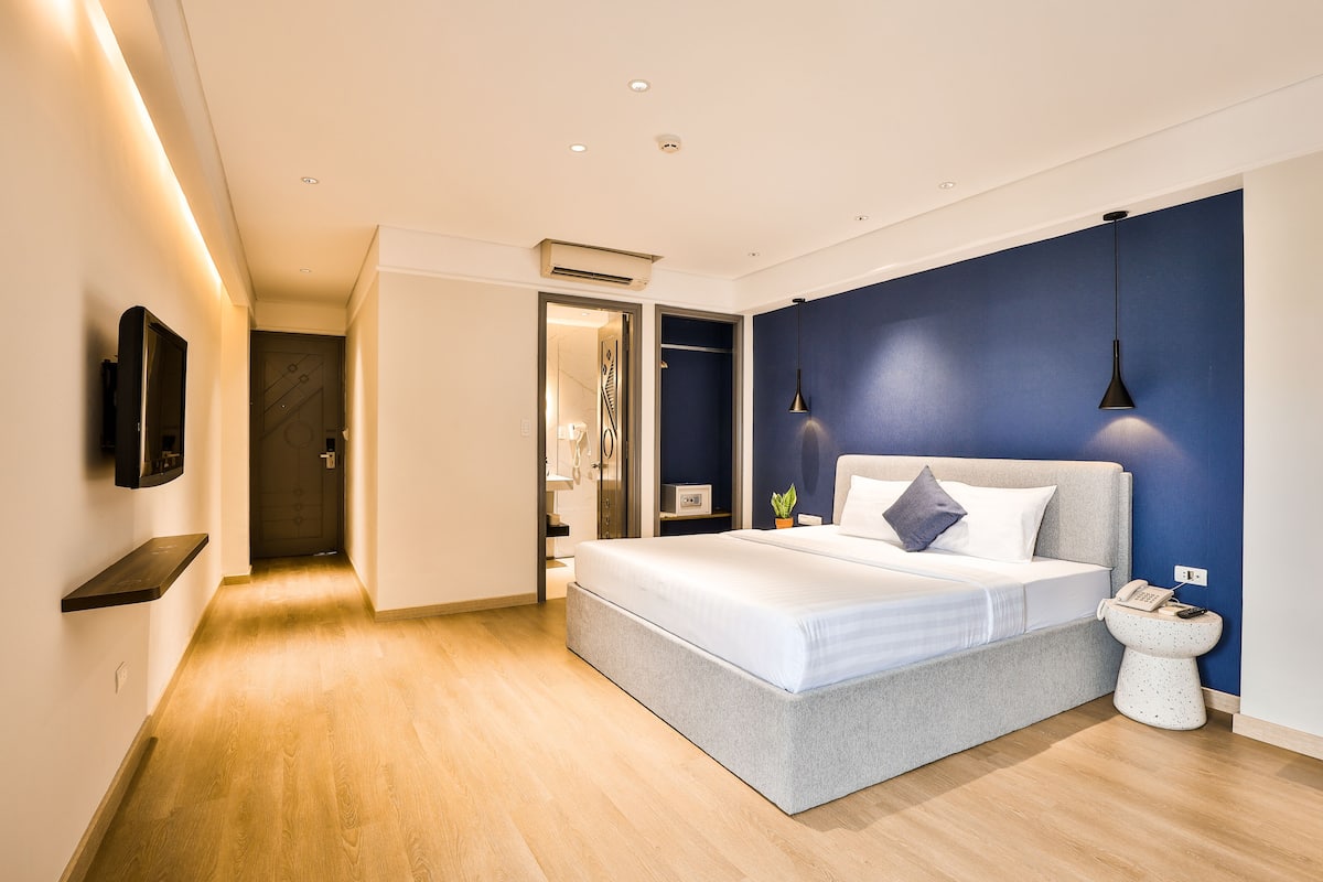 A modern bedroom with a large bed, bedside table, and a wall-mounted TV.