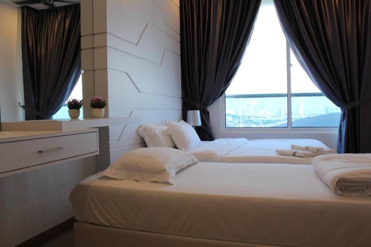 Une chambre d’hôtel avec un lit, une table de chevet, un miroir et une fenêtre avec des rideaux.