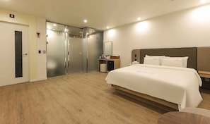 Une chambre d’hôtel avec un lit, un bureau, un miroir et une porte.