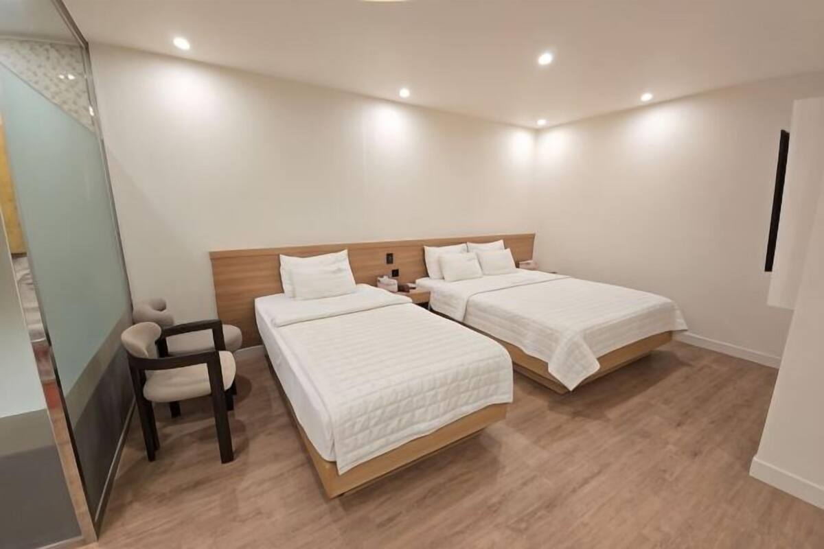 Une chambre d’hôtel avec deux lits, un bureau et une chaise.