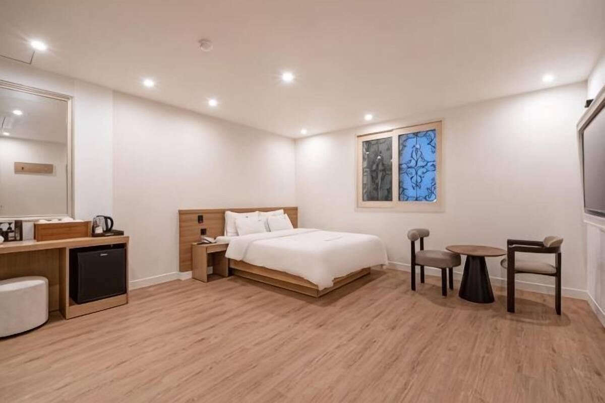 Une chambre d’hôtel comprenant un lit, une table de chevet, un bureau, une chaise et une petite table.