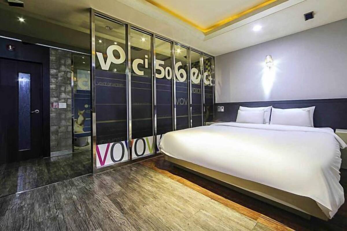 Une chambre moderne avec un grand lit, une armoire aux portes en verre et un mur en pierre.