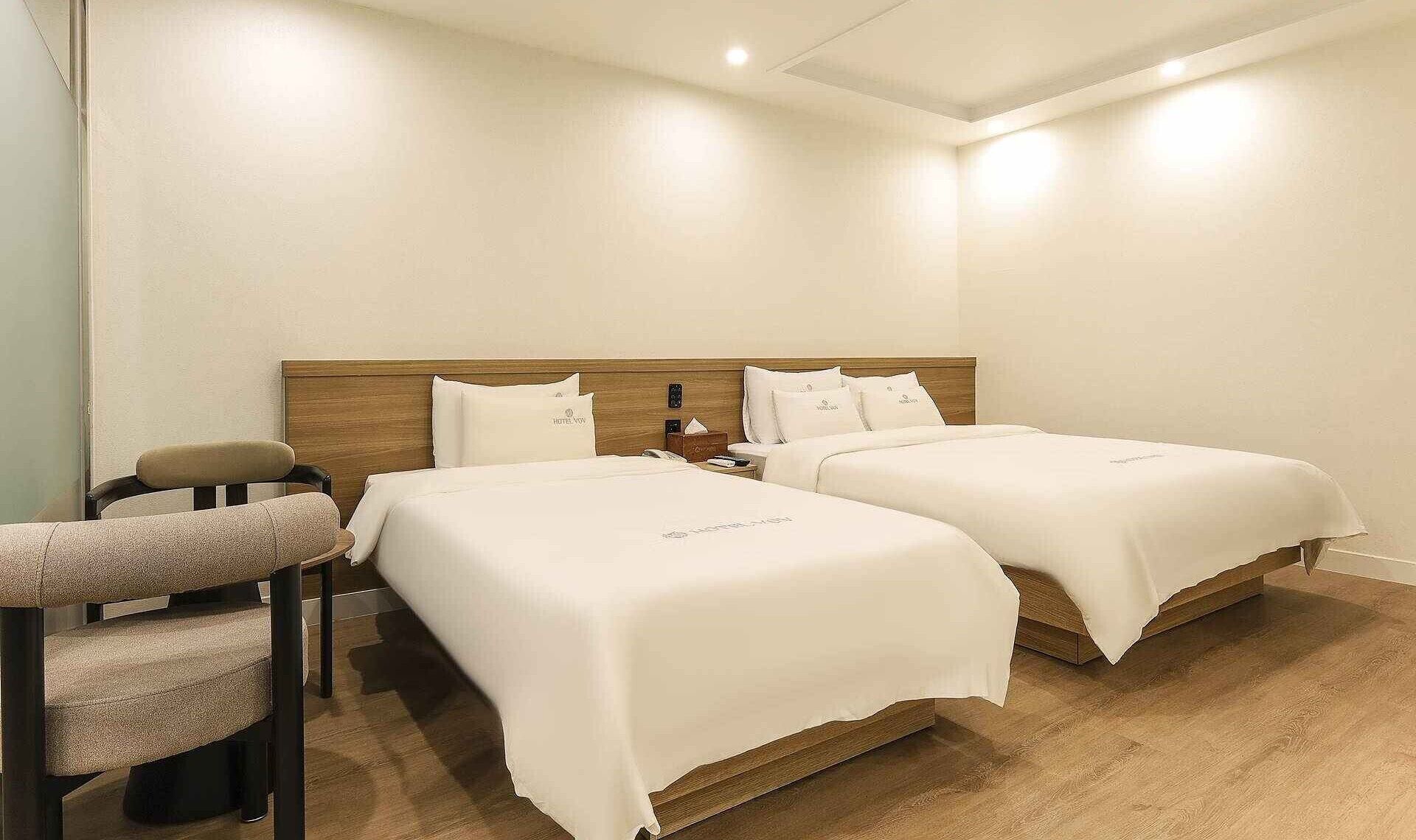 Una habitación de hotel con dos camas, una silla y una mesita de noche.