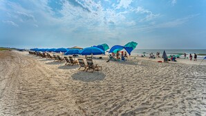 Ein Strand mit Reihen aus blauen Sonnenschirmen und Liegestühlen.