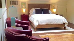 Un dormitorio con una cama, dos mesitas de noche, un tocador, una silla roja y una alfombra marrón.