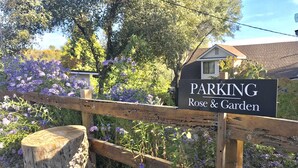 A wooden fence with a sign that reads "PARKING Rose & Garden."