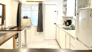 A compact kitchen with a wooden table, a white refrigerator, and a sink.