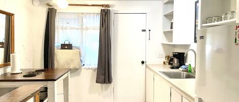 A compact kitchen with a wooden table, a white refrigerator, and a sink.