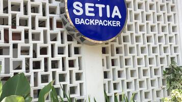 A blue sign with the text "SETIA BACKPACKER" against a white lattice structure.