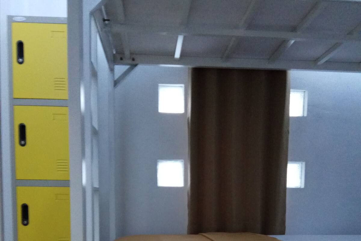 A room with bunk beds, a window, and a yellow storage unit.