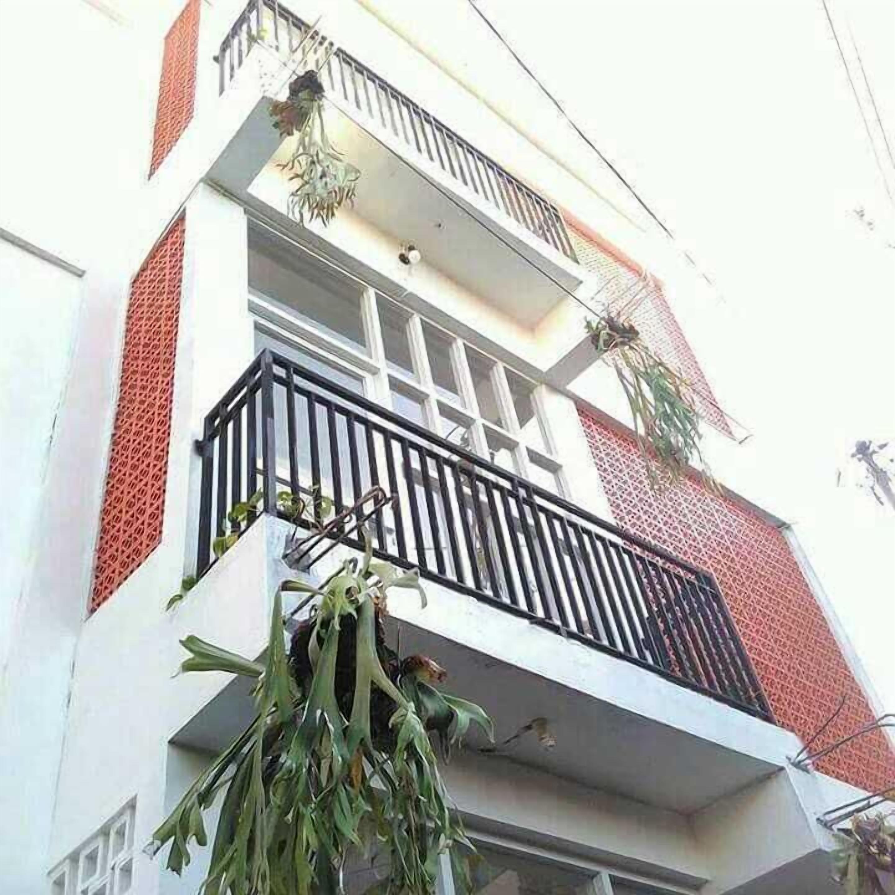 A multi-story building with balconies, some with plants.
