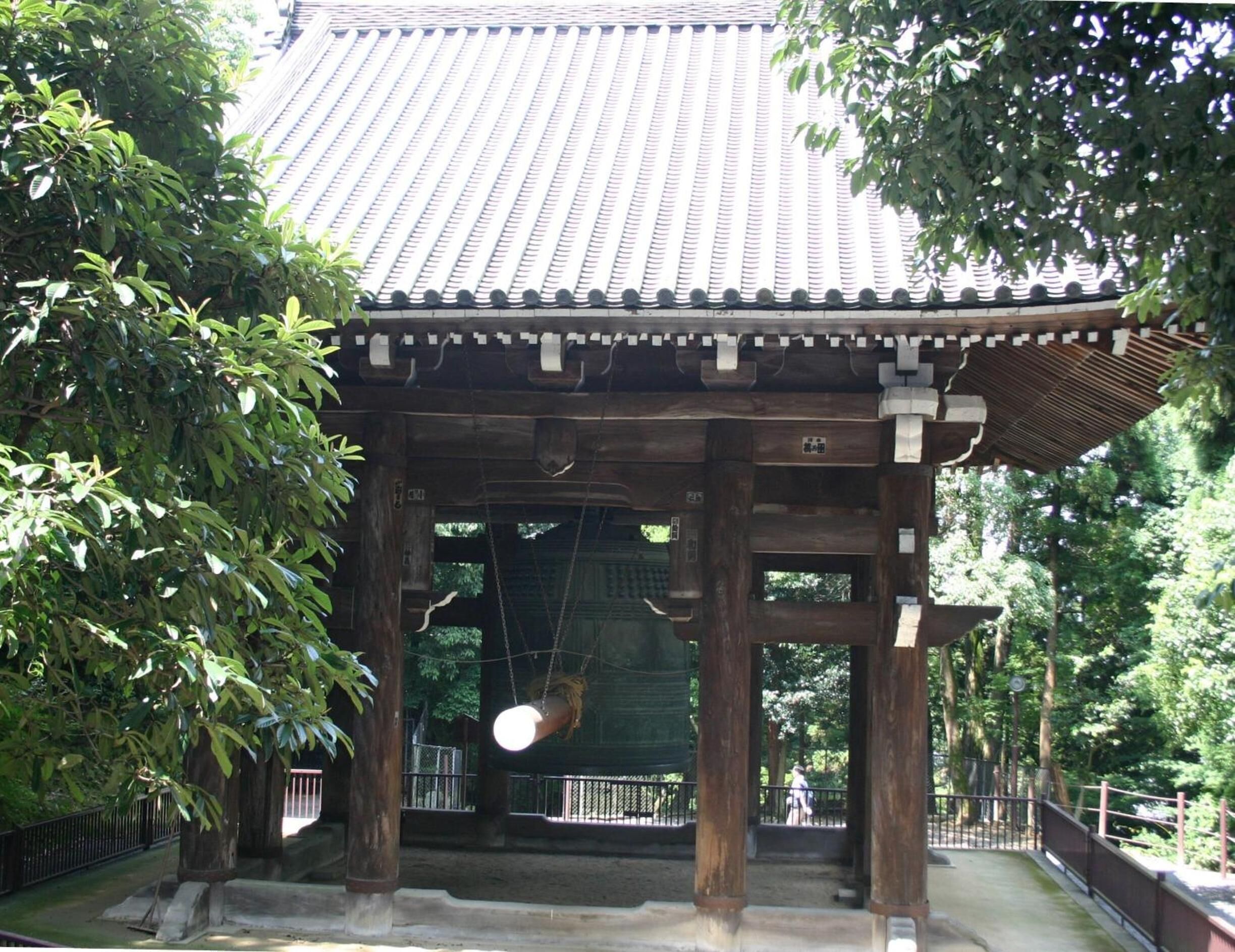 A traditional Japanese pavilion with a tiled roof, surrounded by lush greenery.