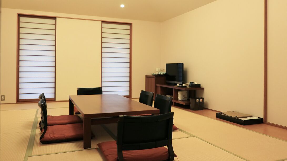 A traditional Japanese-style room with tatami flooring, a low table, and black chairs.