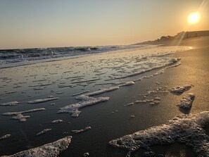 Una playa con olas y huellas en la arena.