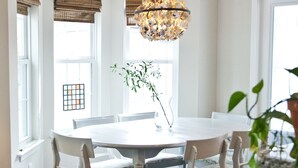 A dining area with a round table, six chairs, and a chandelier.