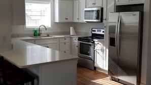 A modern kitchen with white cabinets, a stainless steel refrigerator, a microwave, and an oven.