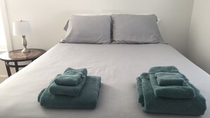 A neatly made bed with two folded towels on either side.