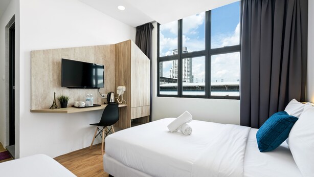 A hotel room with a bed, a desk, a TV, and a large window with a city view. - Rica Hotel (Subang Jaya)