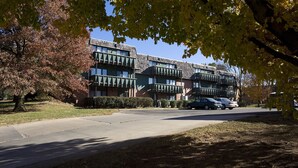 A multi-story building with a brick facade and green awnings, surrounded by trees and parked cars. - Heritage Suites 43 (Manhattan)