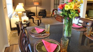 A dining area with a table set for two, a vase of flowers, and a lamp. - Heritage Suites 43 (Manhattan)