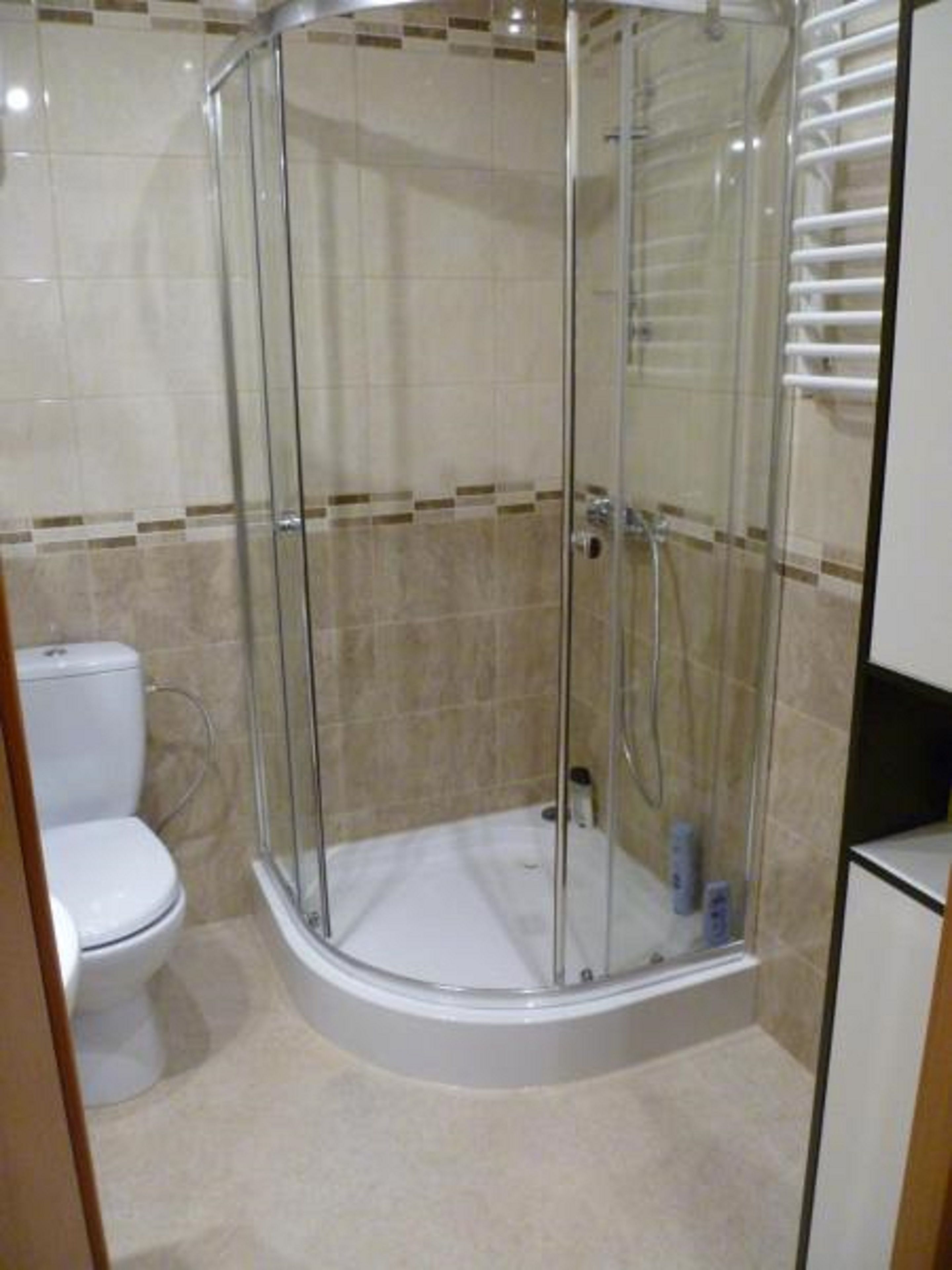 Un box de ducha con paredes de cristal, un inodoro y un perchero en un baño.