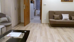 Una sala de estar con un sofá, una mesa de centro y una puerta que da a la cocina.