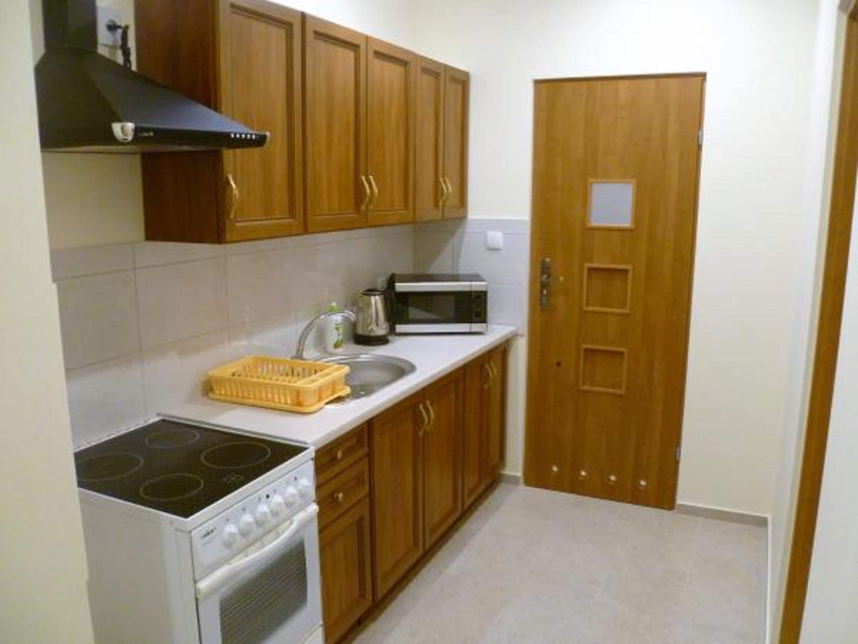A compact kitchen with wooden cabinets, a stove, a microwave, and a sink.