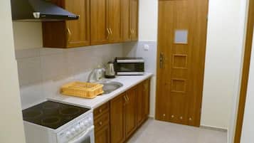 A compact kitchen with wooden cabinets, a stove, a microwave, and a sink.