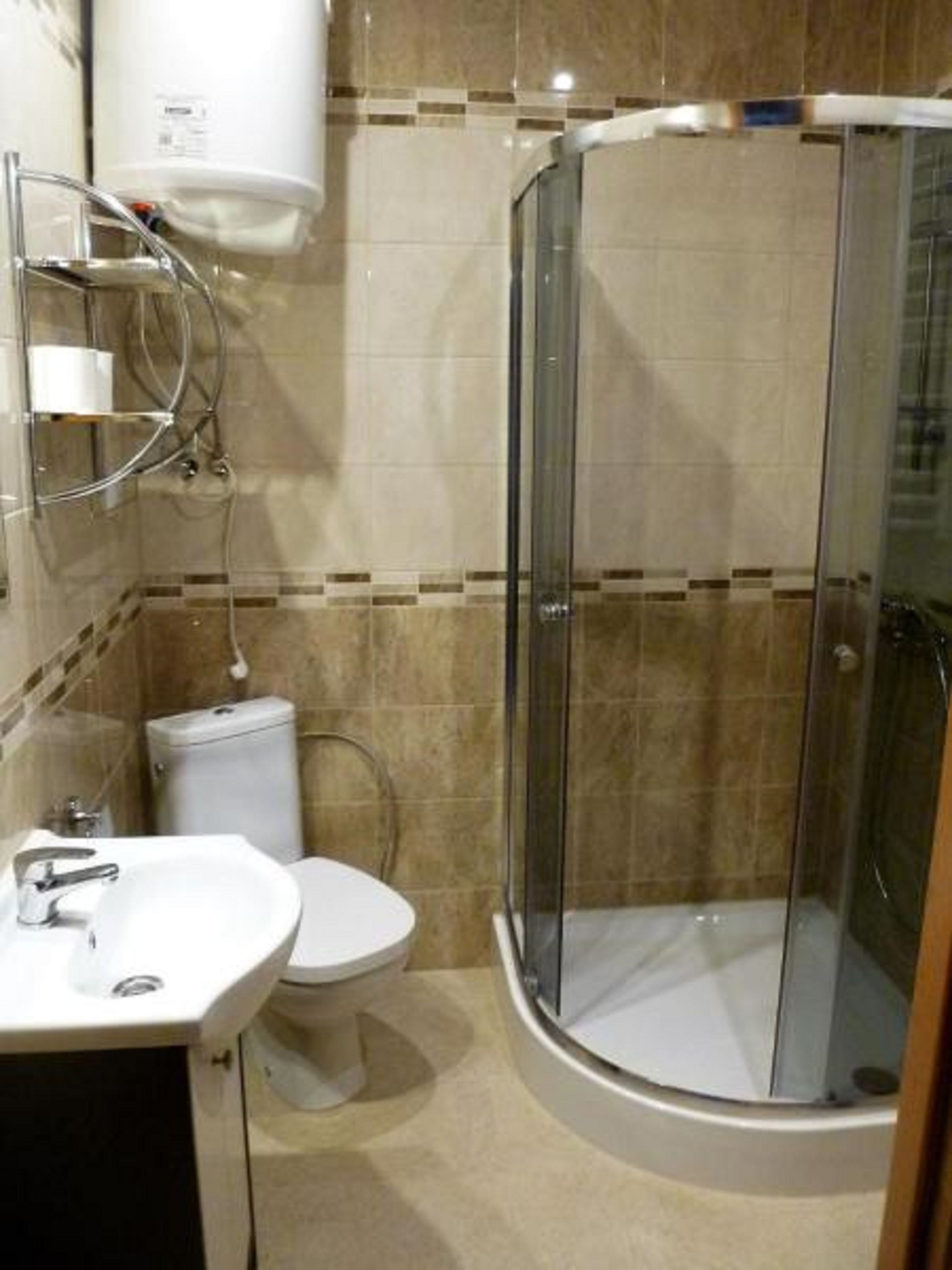 A bathroom with a glass-enclosed shower, a toilet, and a sink.