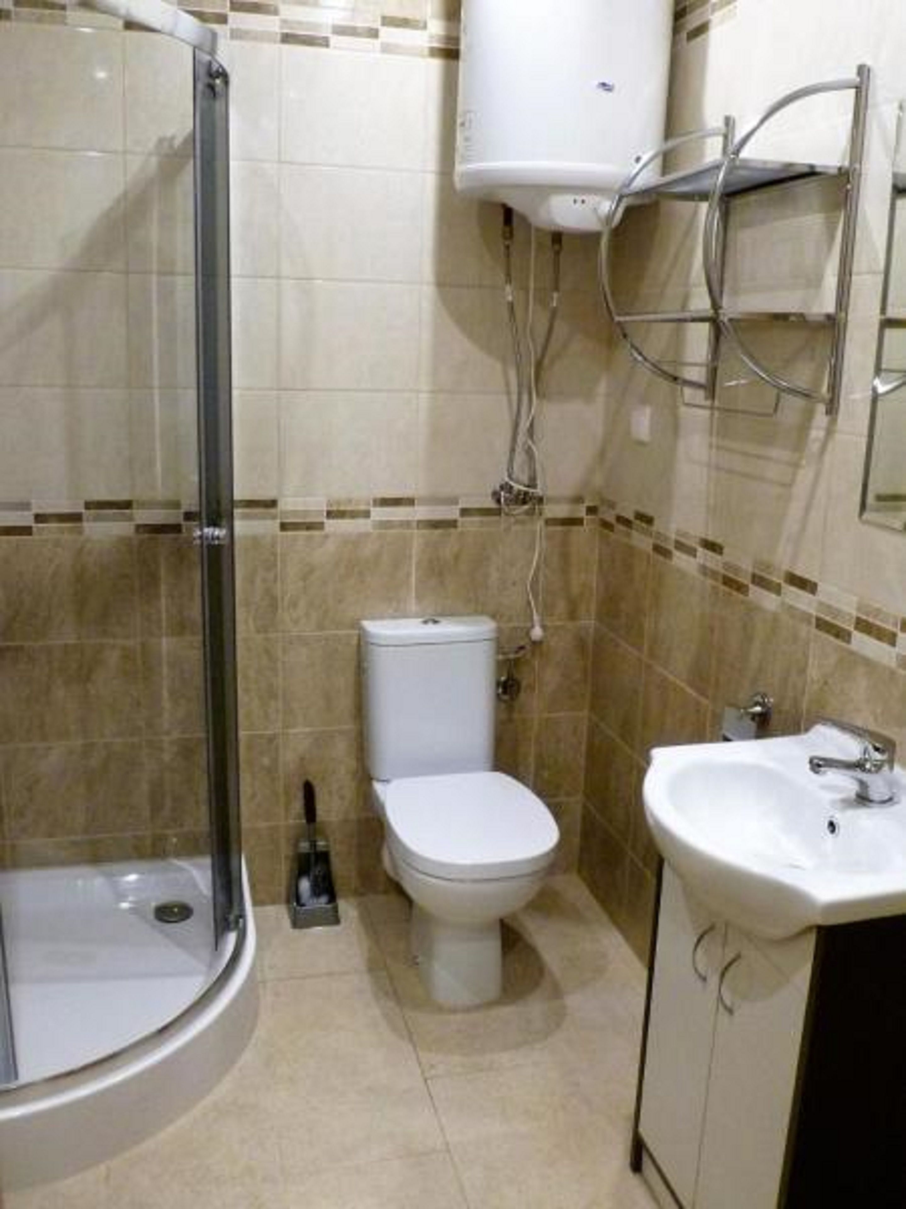 Un baño con cabina de ducha de vidrio, inodoro y lavabo.