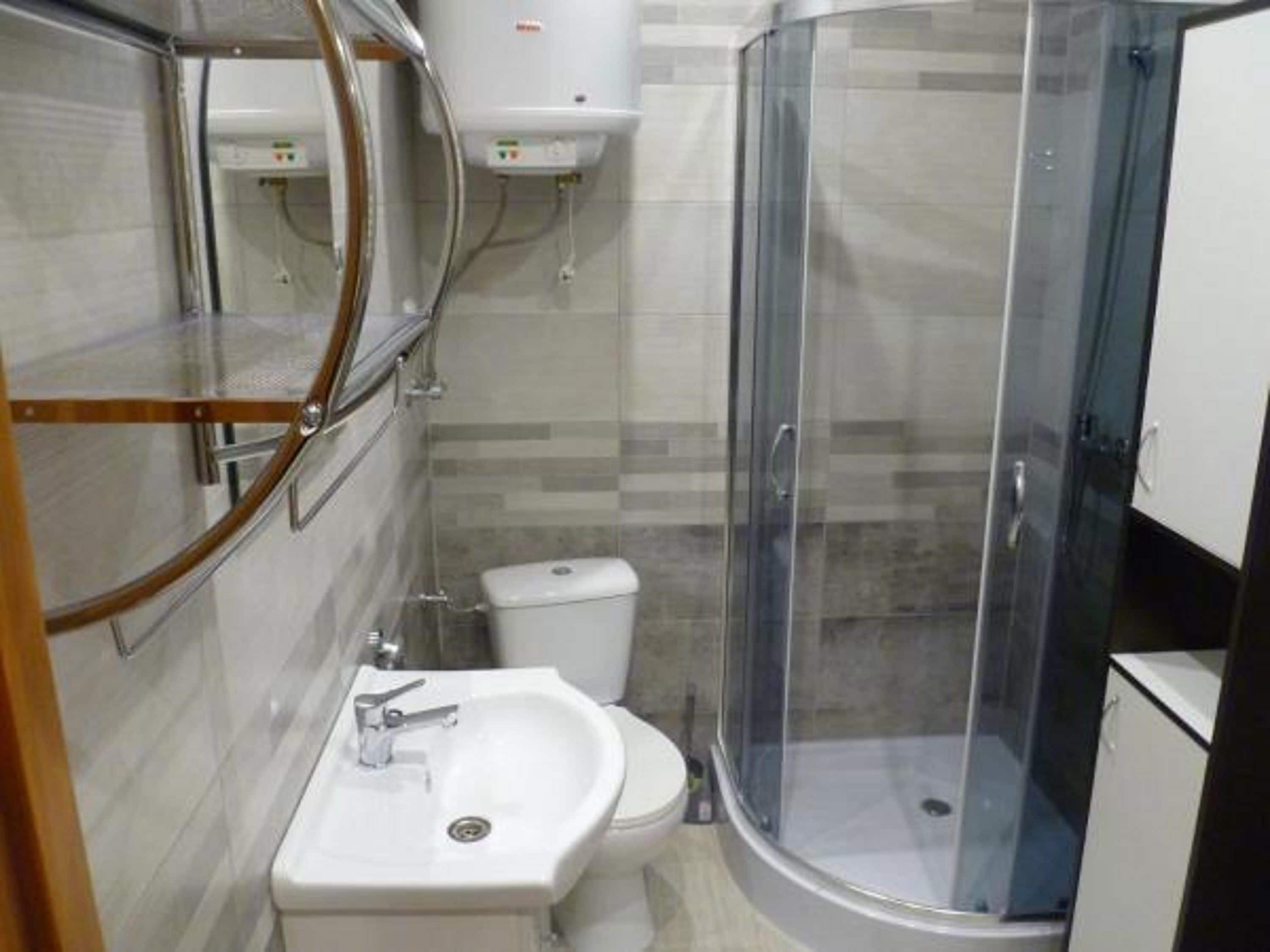A compact bathroom with a shower enclosure, a sink, and a toilet.