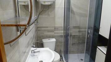 A compact bathroom with a shower enclosure, a sink, and a toilet.