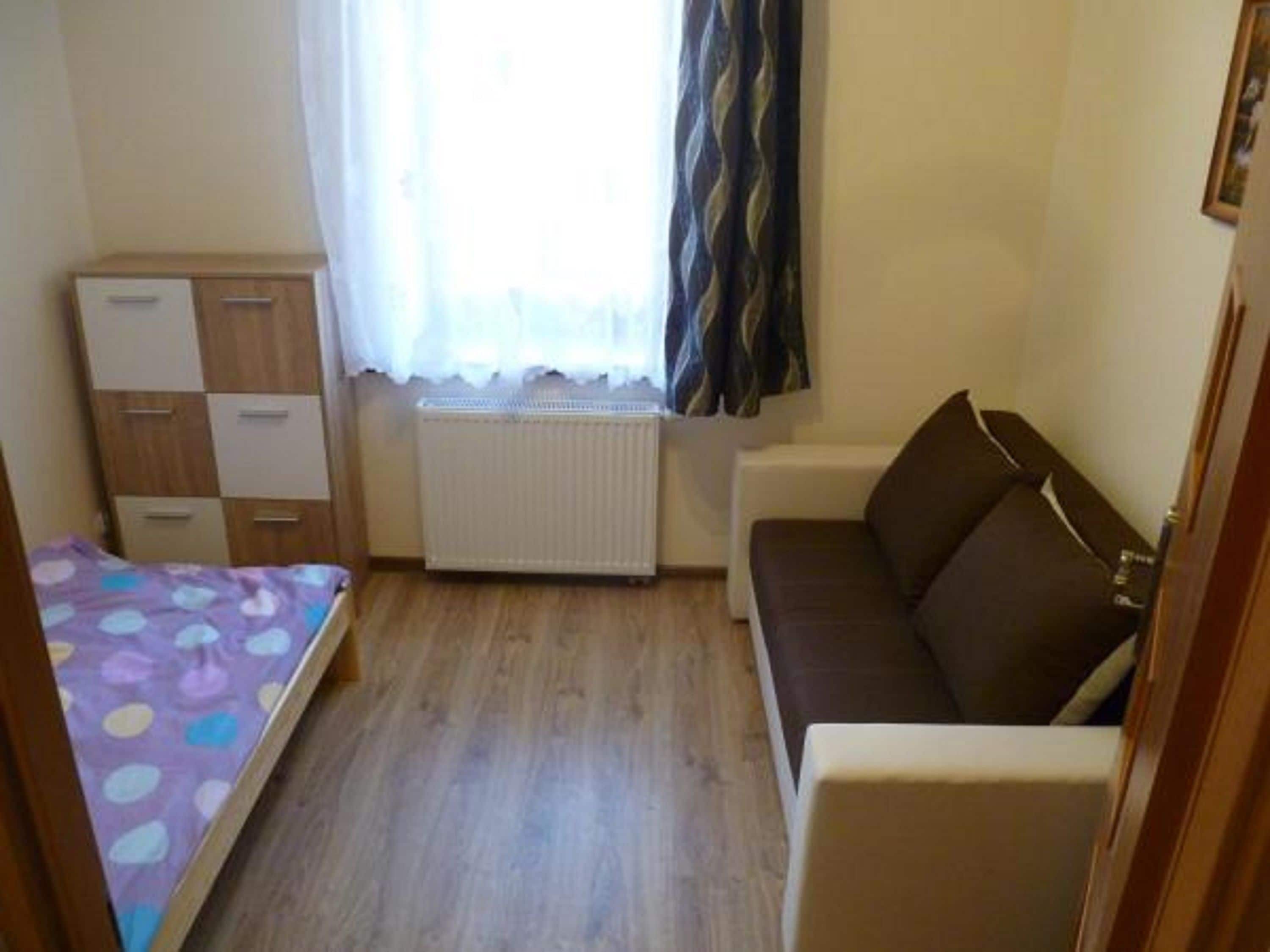 Une petite pièce comprenant un lit, un canapé, une armoire et un radiateur.