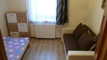 Une petite pièce comprenant un lit, un canapé, une armoire et un radiateur.