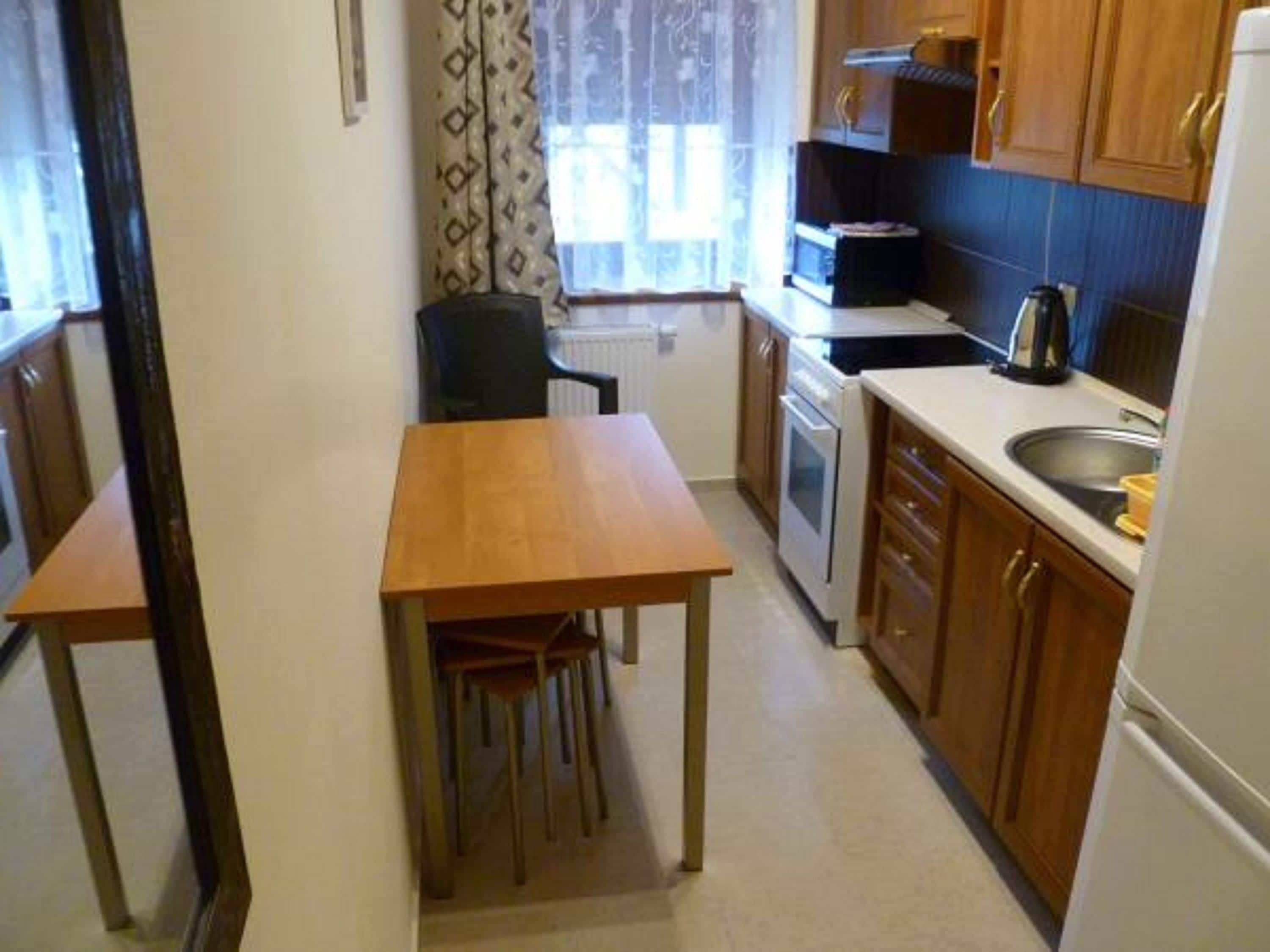 Cucina compatta con mobili in legno, fornello e lavandino.