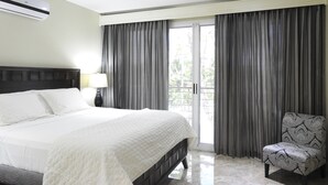 Ein Hotelzimmer mit einem Bett, einem Sessel, einem Deckenventilator und einem Fenster mit Vorhängen.