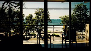 Blick aus einem Gebäude mit großen Fenstern auf einen Strand.