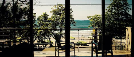Blick aus einem Gebäude mit großen Fenstern auf einen Strand.