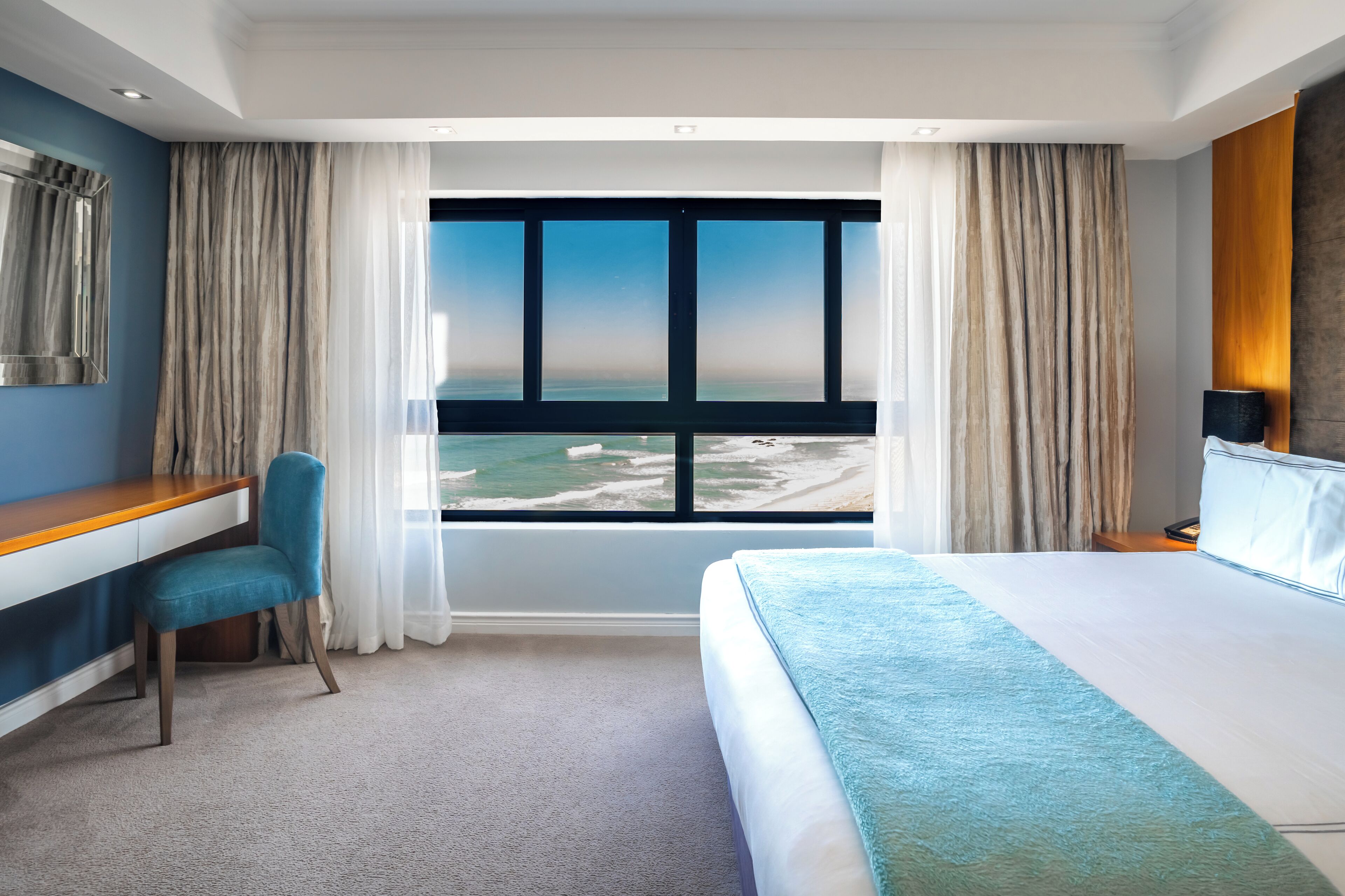 Une chambre d’hôtel avec un grand lit, un bureau et une vue sur la plage.