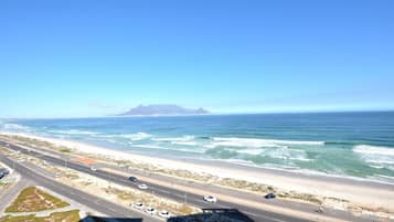 A coastal highway with vehicles, a beach, and ocean waves.