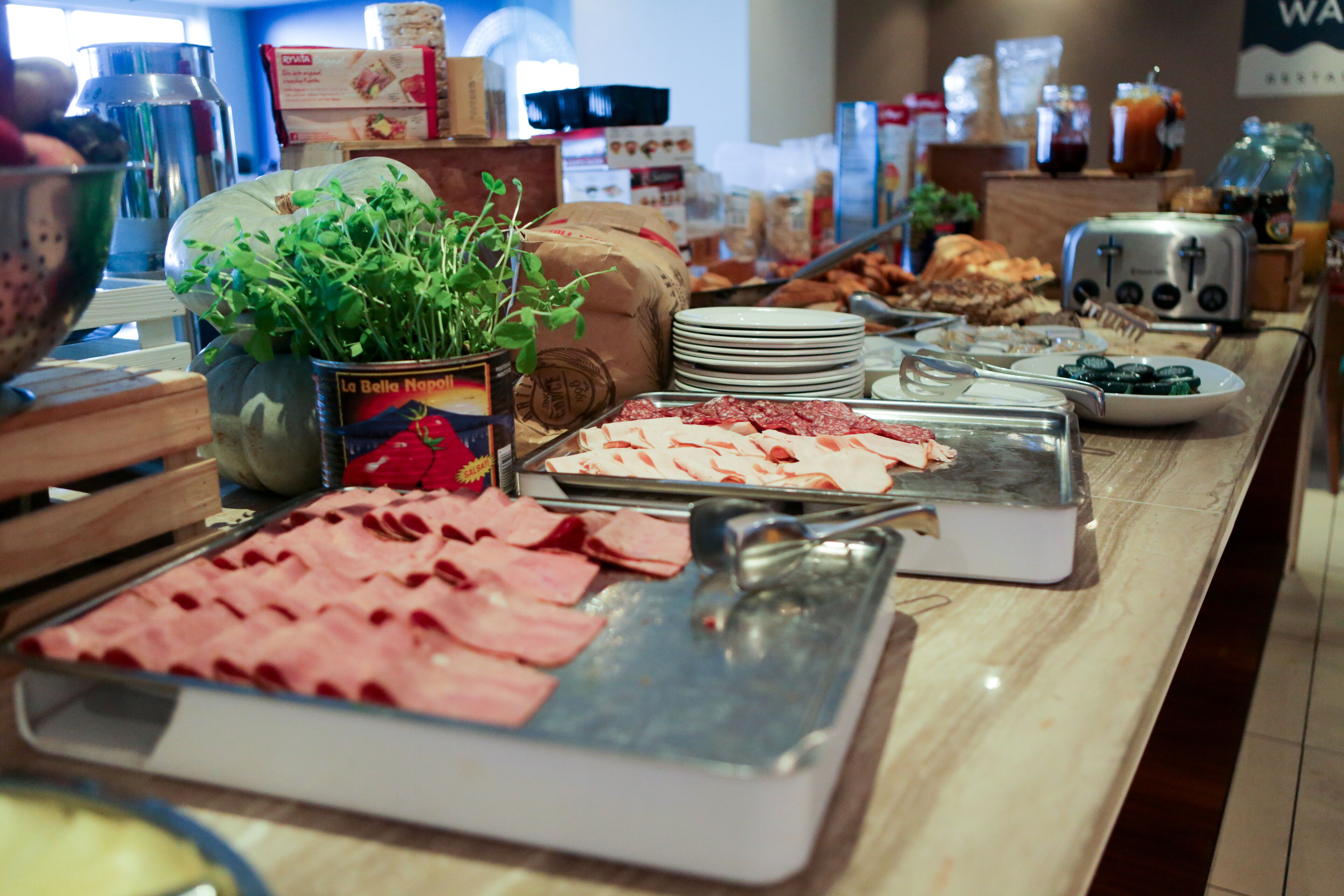 A buffet with various food items including meats, cheeses, and fresh greens.