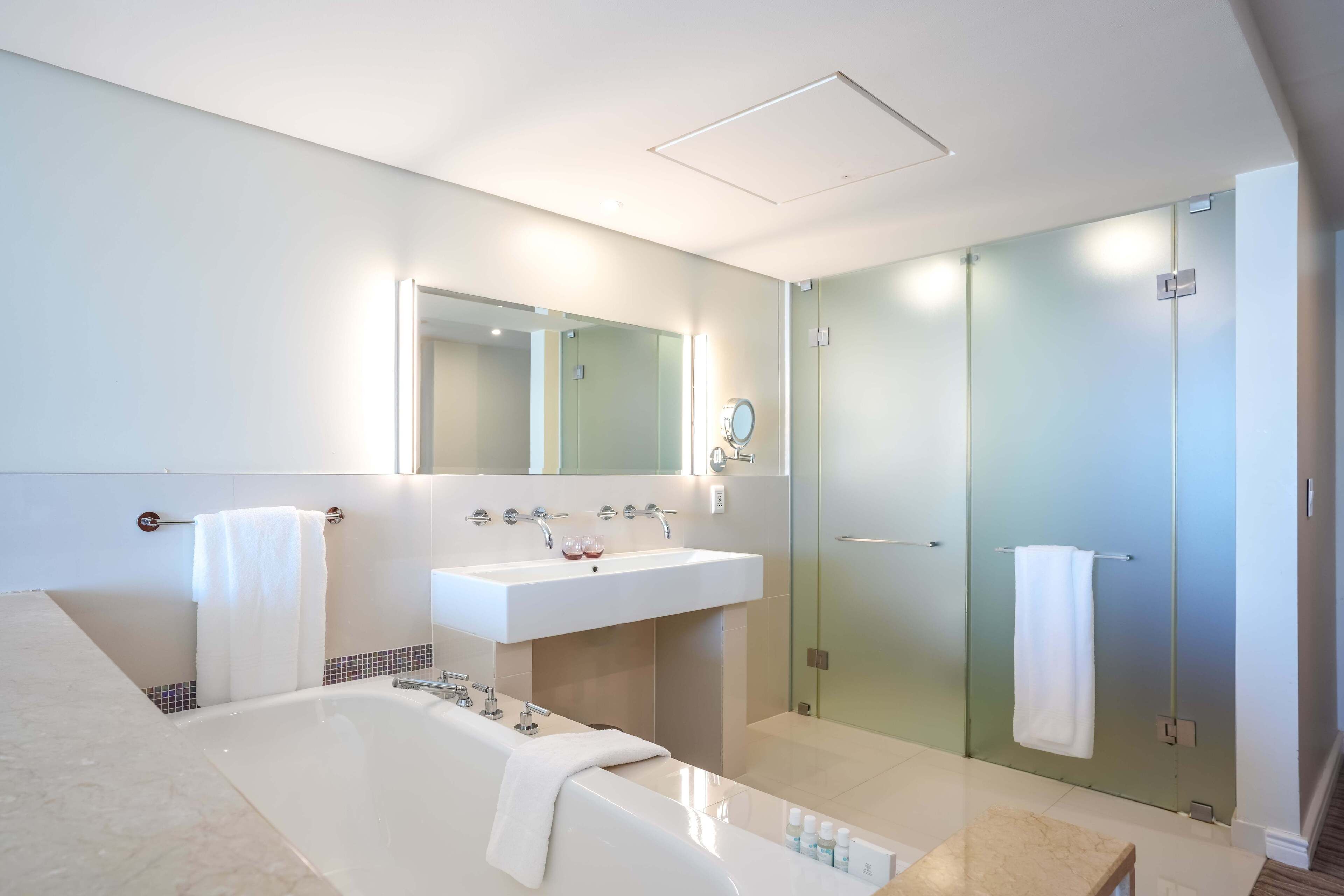Un baño moderno con una bañera grande, un lavabo y una ducha con mampara de vidrio.