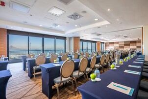 A conference room with tables and chairs, large windows with a view, and a modern ceiling design.