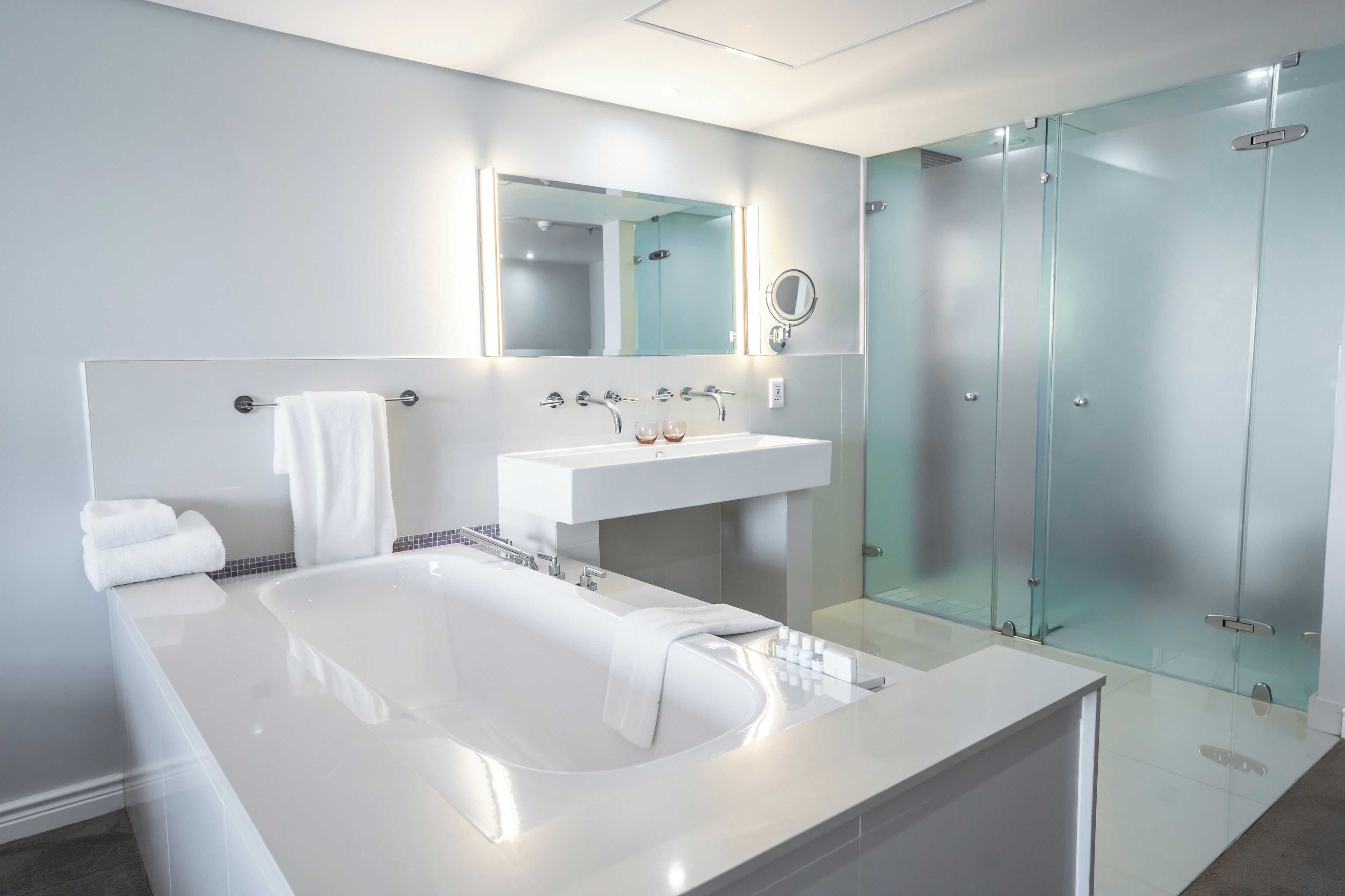 A modern bathroom with a large bathtub, a white sink, and a glass shower enclosure.