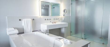 A modern bathroom with a large bathtub, a white sink, and a glass shower enclosure.