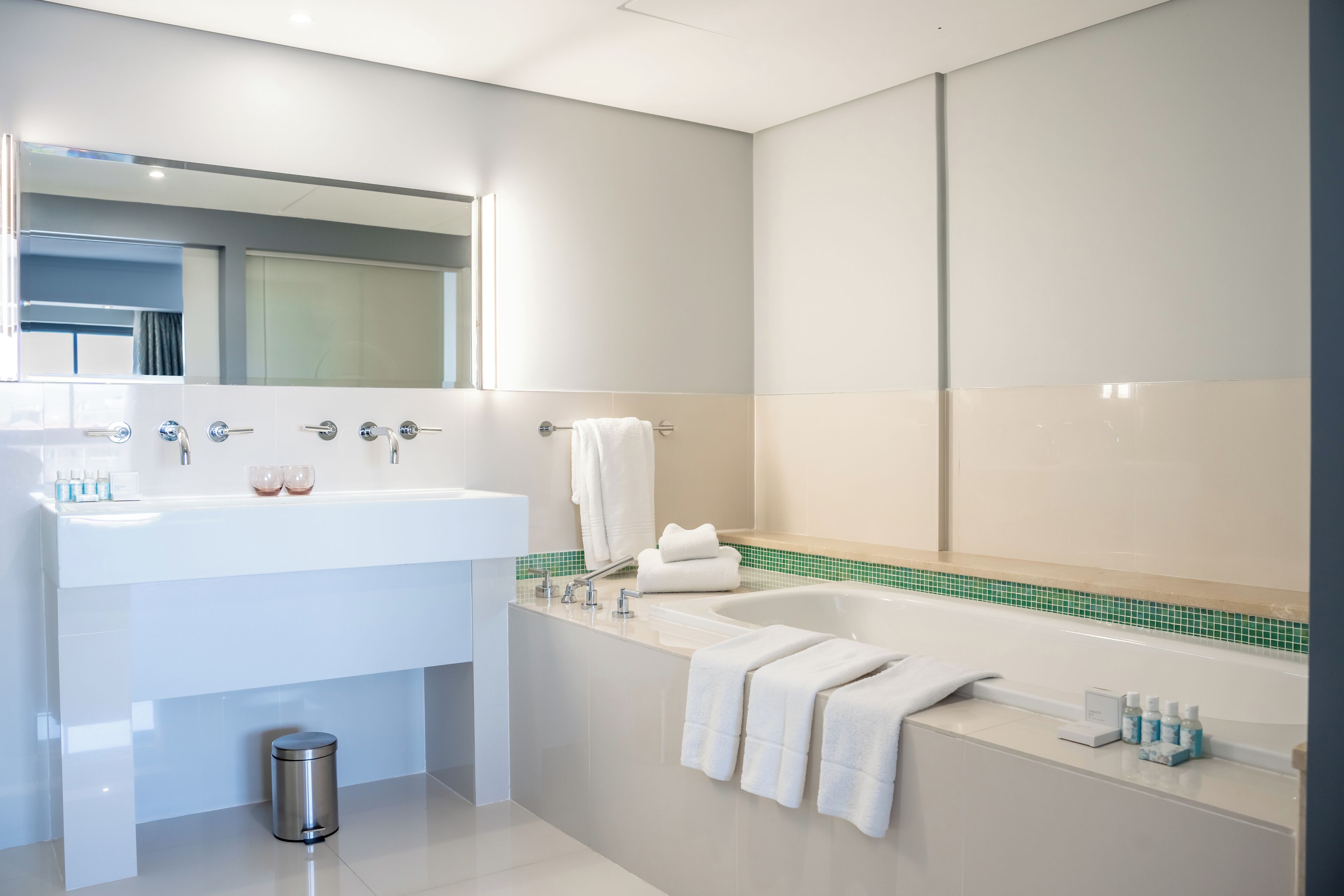 Un baño moderno con un lavabo blanco, una bañera y un espejo.