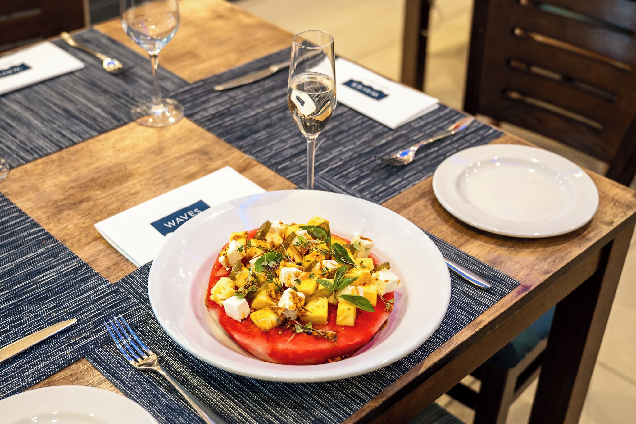 A table with a plate of food, a glass of water, and a menu.