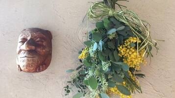 Un masque décoratif fixé au mur et une composition florale avec des feuilles vertes et des fleurs jaunes.